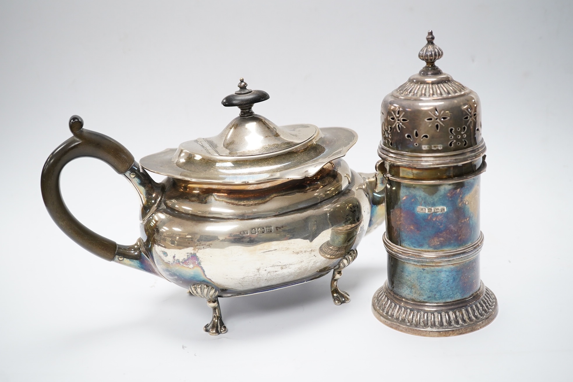 An Edwardian bachelor's silver teapot, Henry Wigful?, Sheffield, 1903, together with a George V silver lighthouse sugar caster by Atkin Brothers, 15.4cm, gross weight 19.5oz. Condition - poor to fair